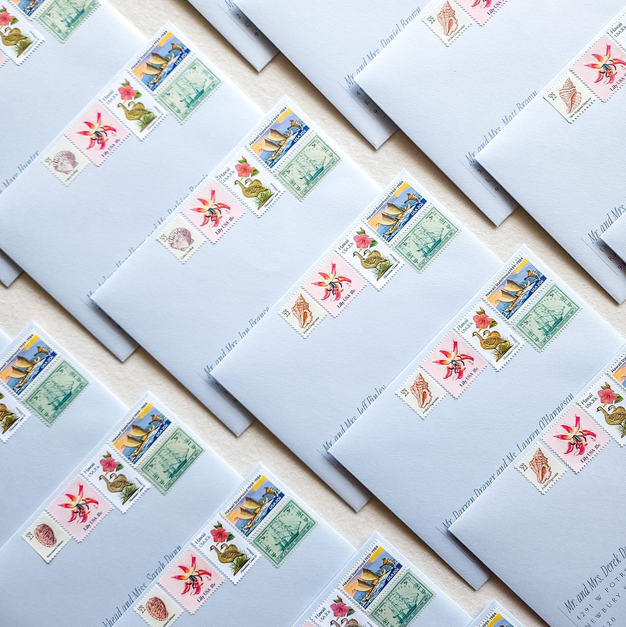 Blue wedding envelopes with hand calligraphy and a collection of vintage postage stamps