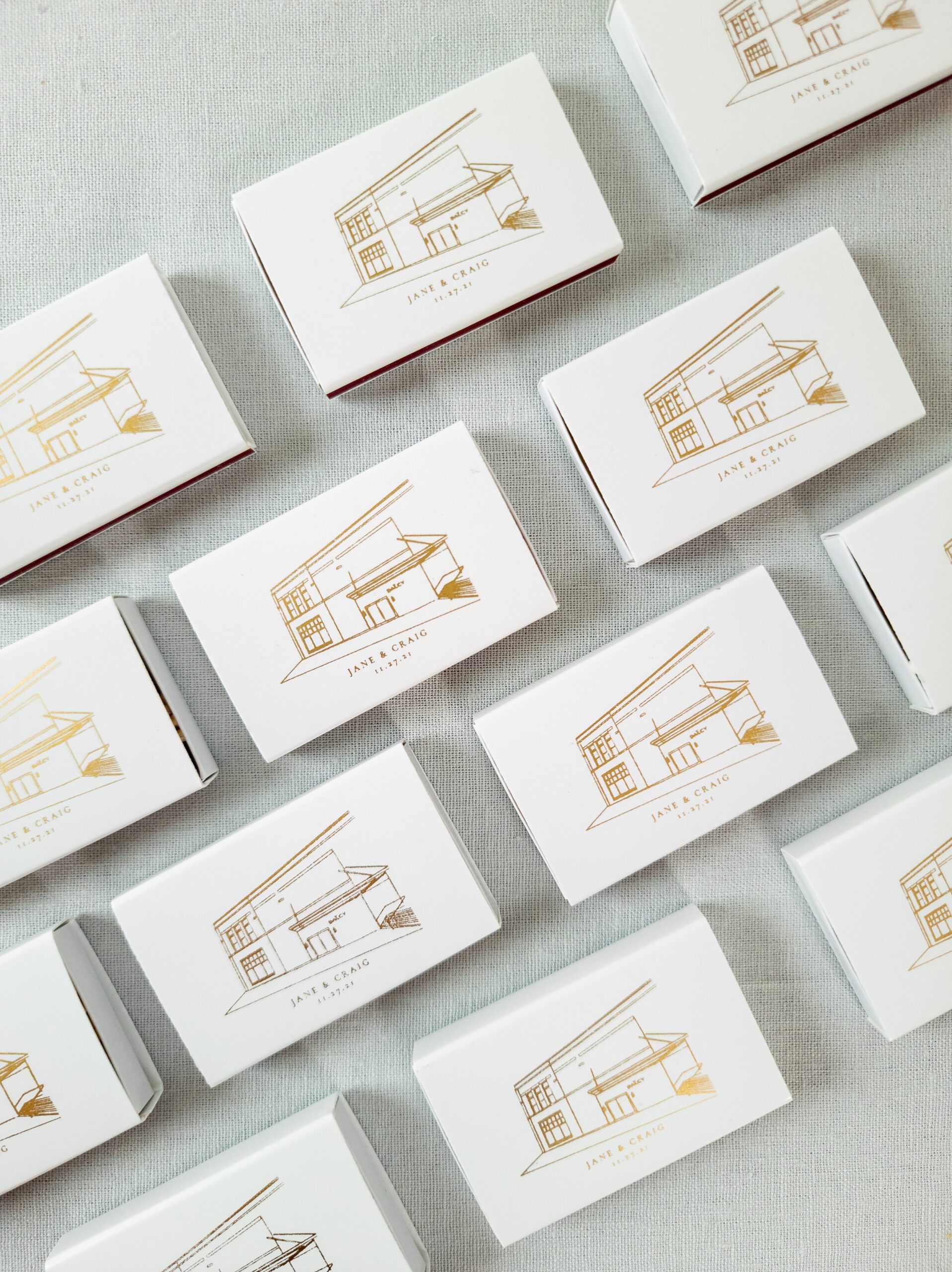 White cocktail napkins and matchboxes with a gold venue illustration