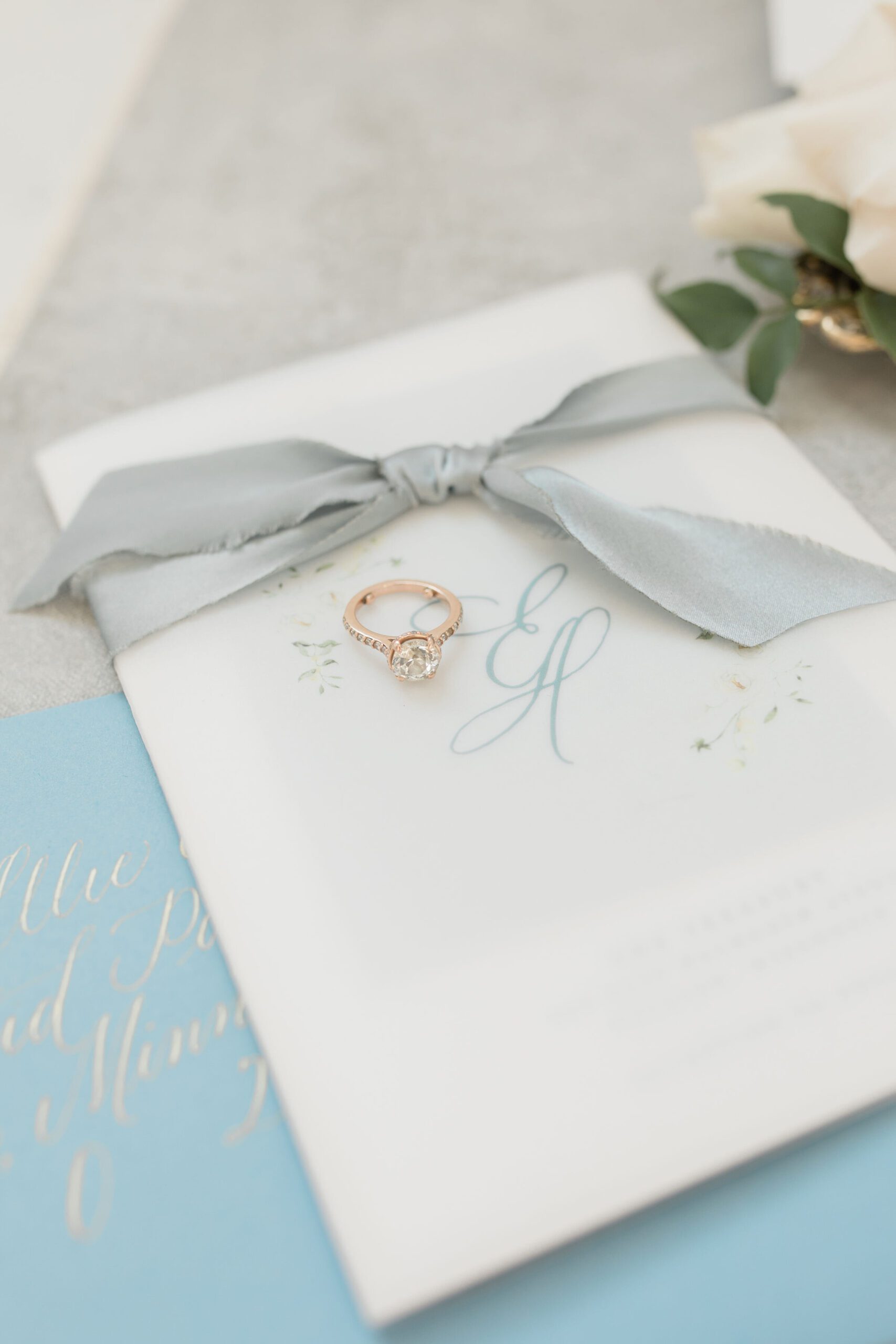 Floral monogram on a vellum invitation wrap tied with pale blue ribbon