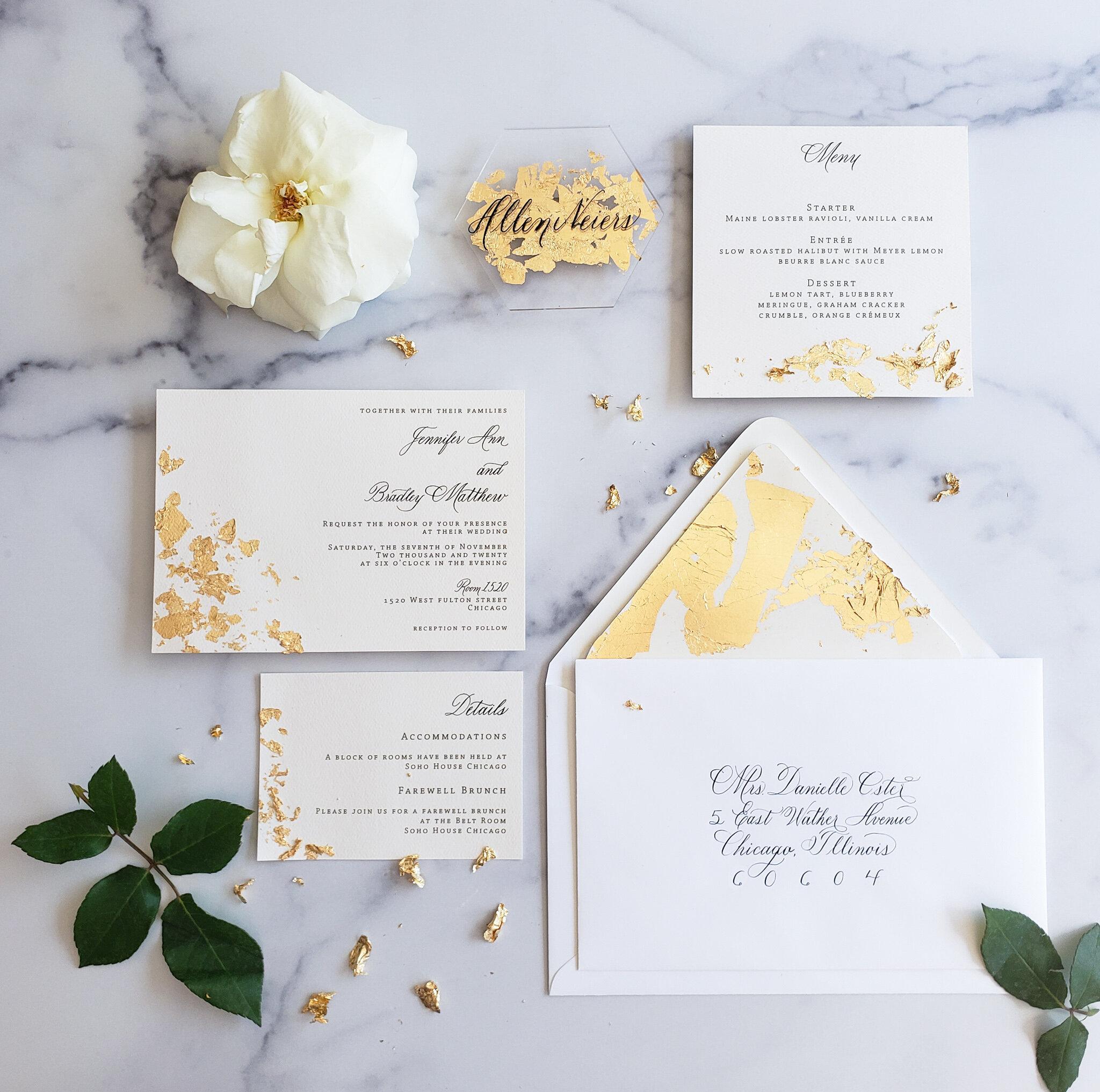 White wedding invitation suite with gold leaf accents and calligraphy