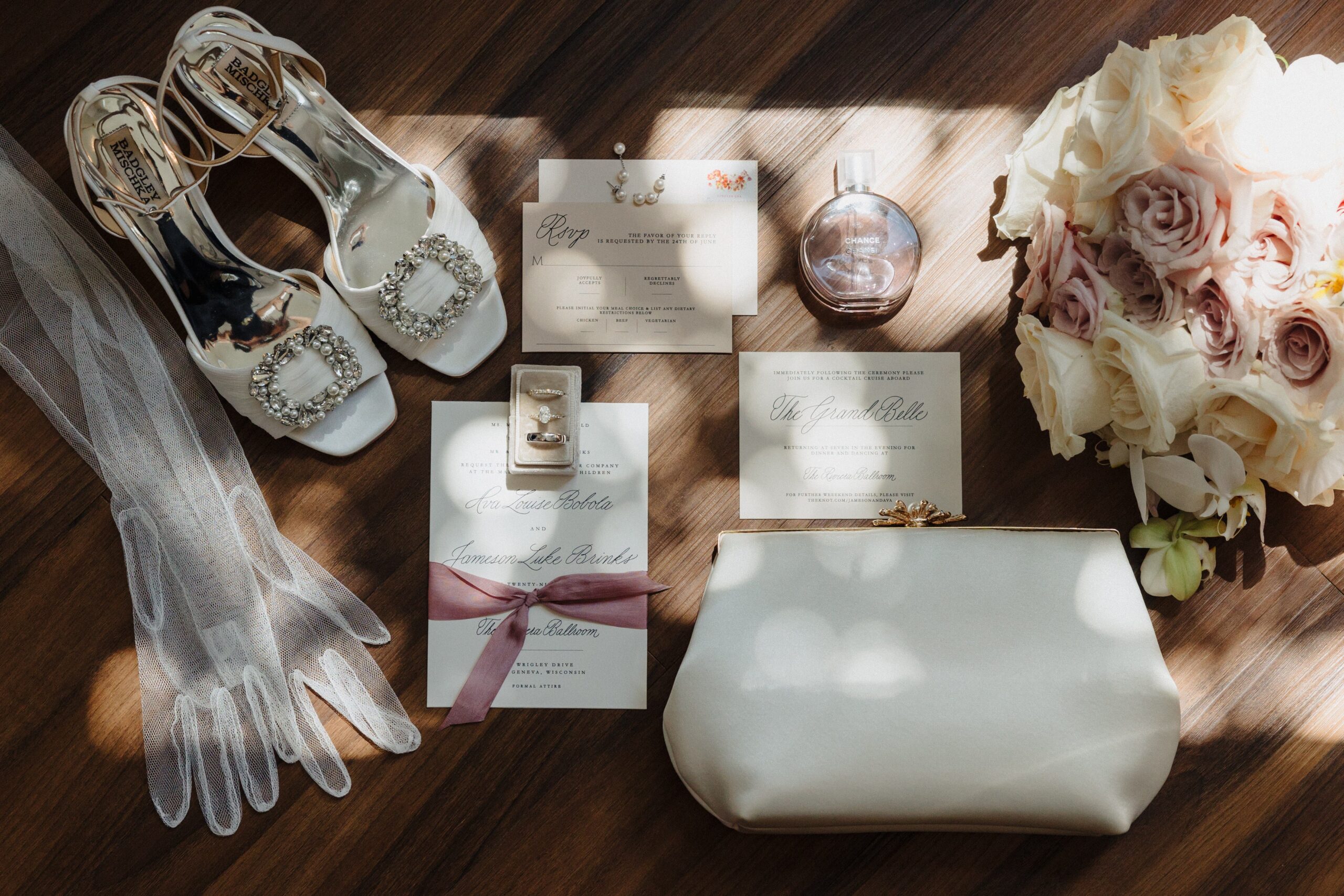 Blush wedding stationery arranged with shoes, ribbon, and flowers