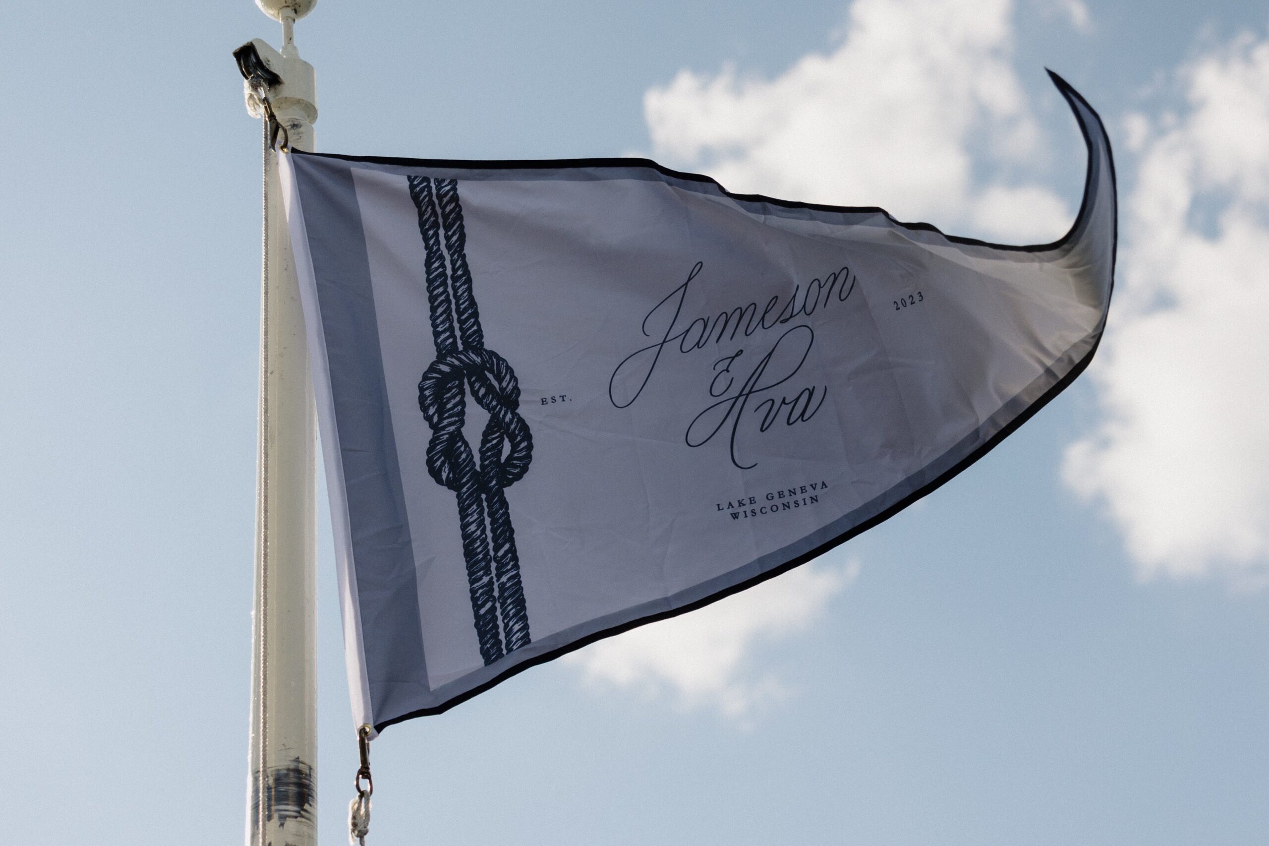Custom calligraphy maritime flag above a lakeside wedding cocktail hour
