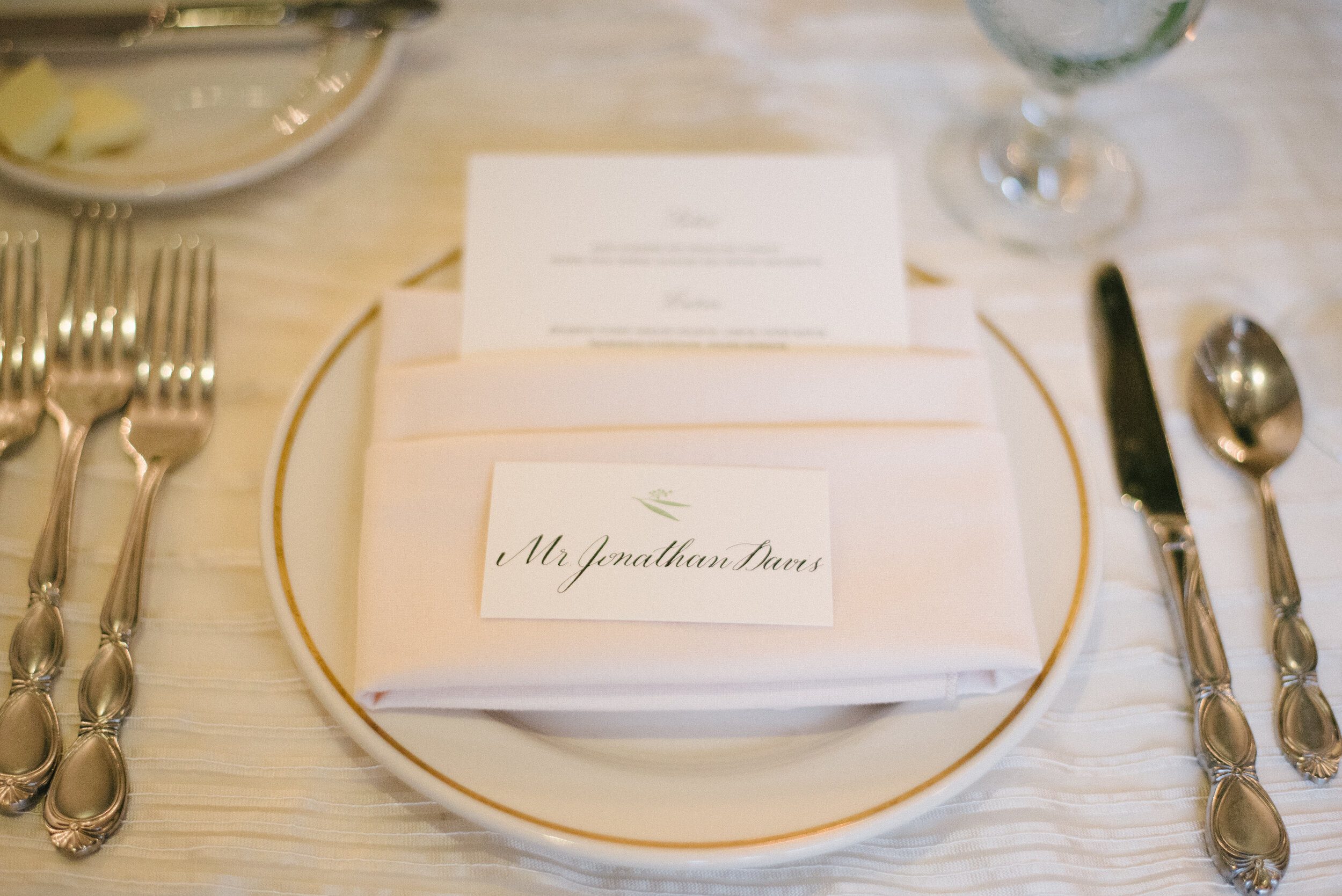 Calligraphy place card on a gold-rimmed plate at Longue Vue Club