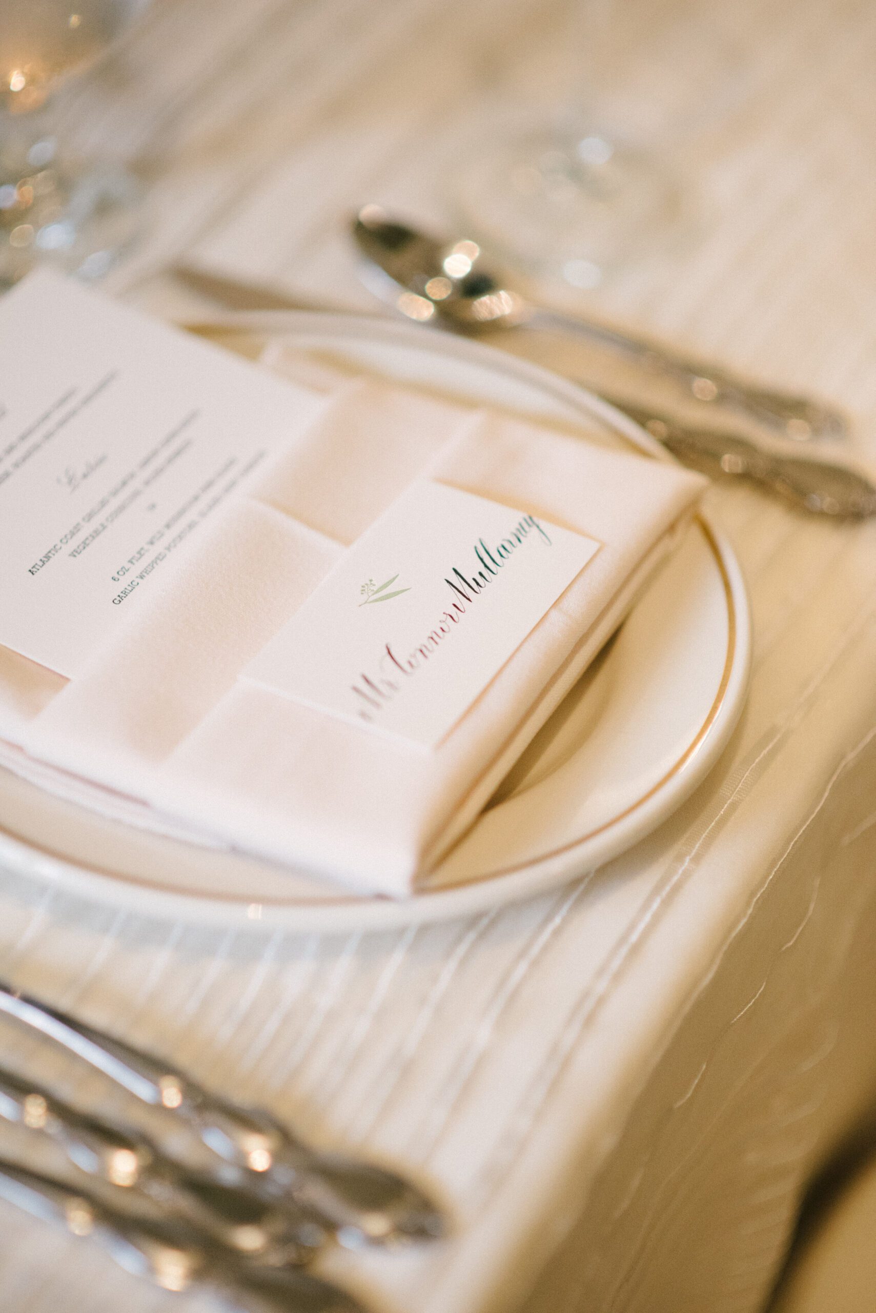 Wedding place card at a formal table setting with gold-rimmed china