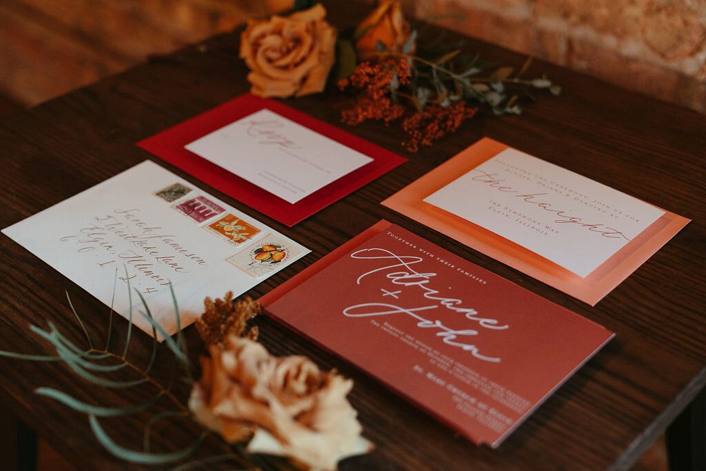 Persimmon and blush invitation cards arranged with autumn flowers