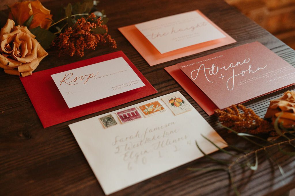 Warm-toned invitation cards and a calligraphy envelope with vintage stamps