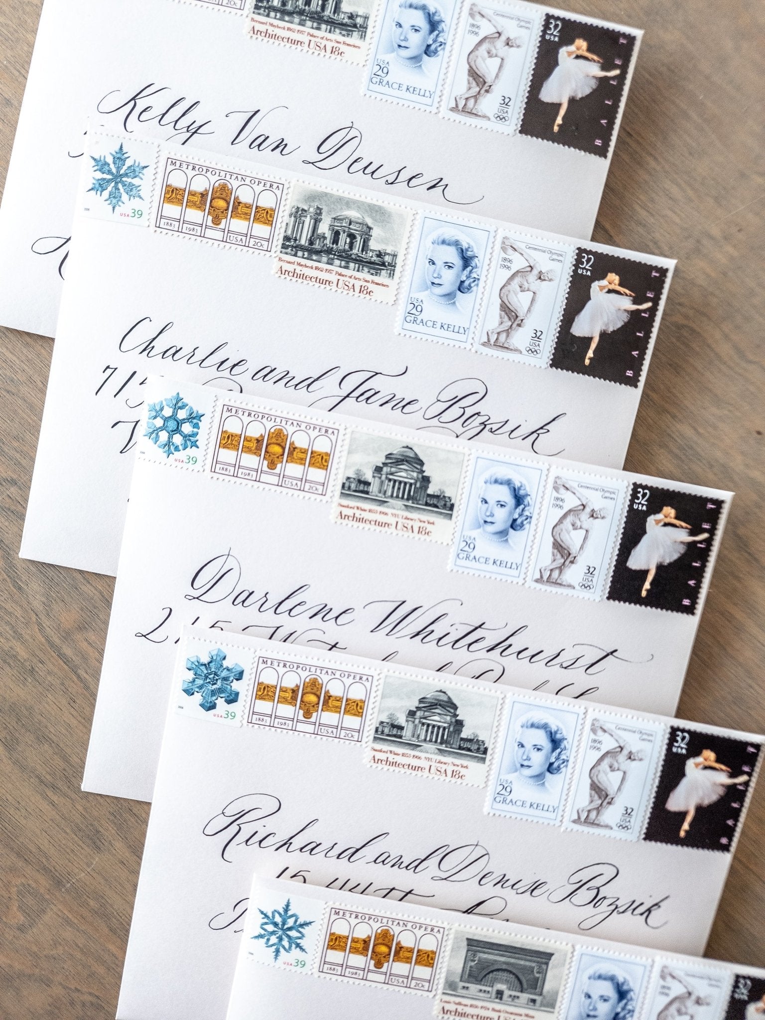 Calligraphy wedding envelopes arranged with curated vintage postage