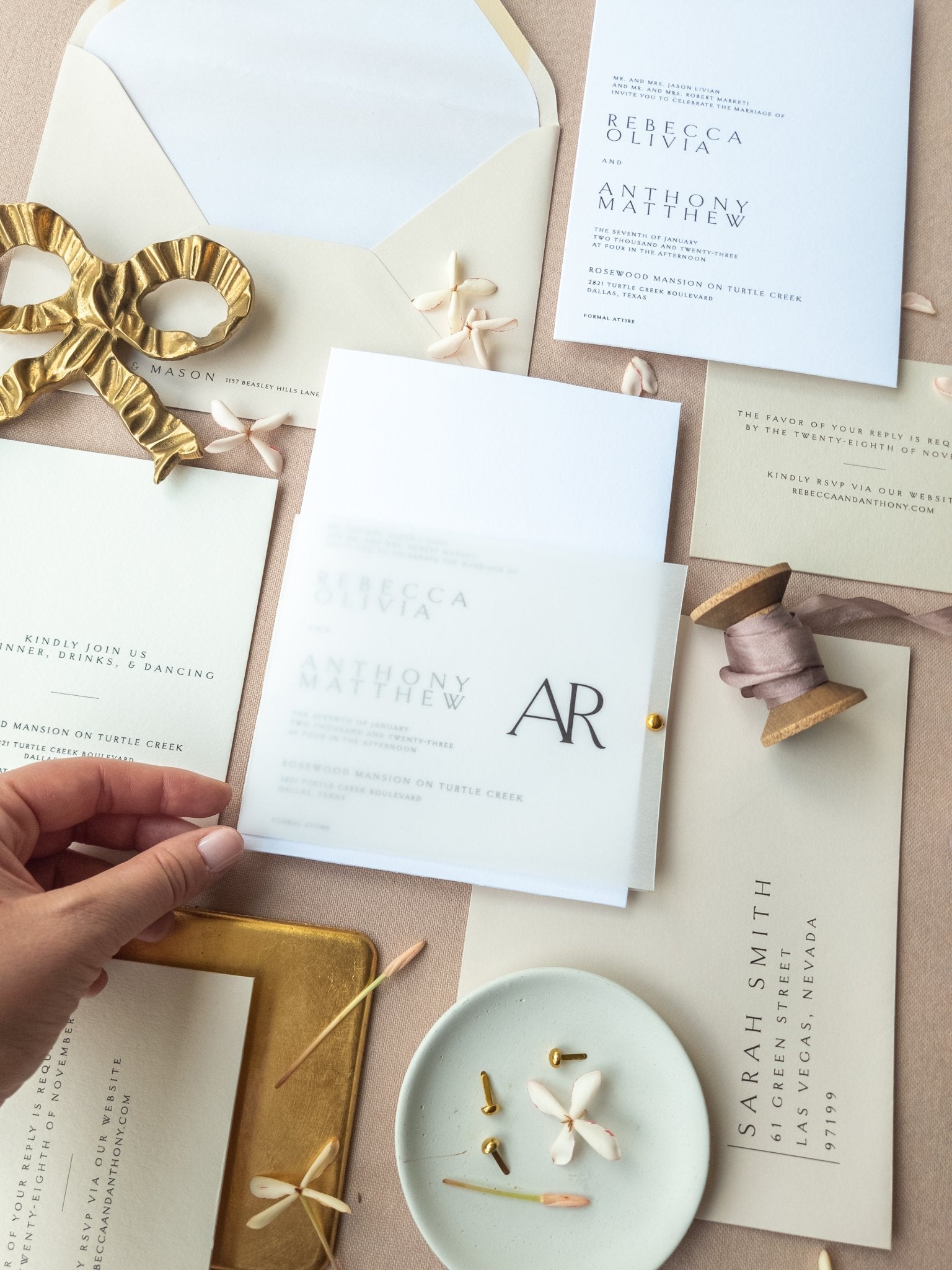 Hand holding a wedding invitation card above the rest of the suite