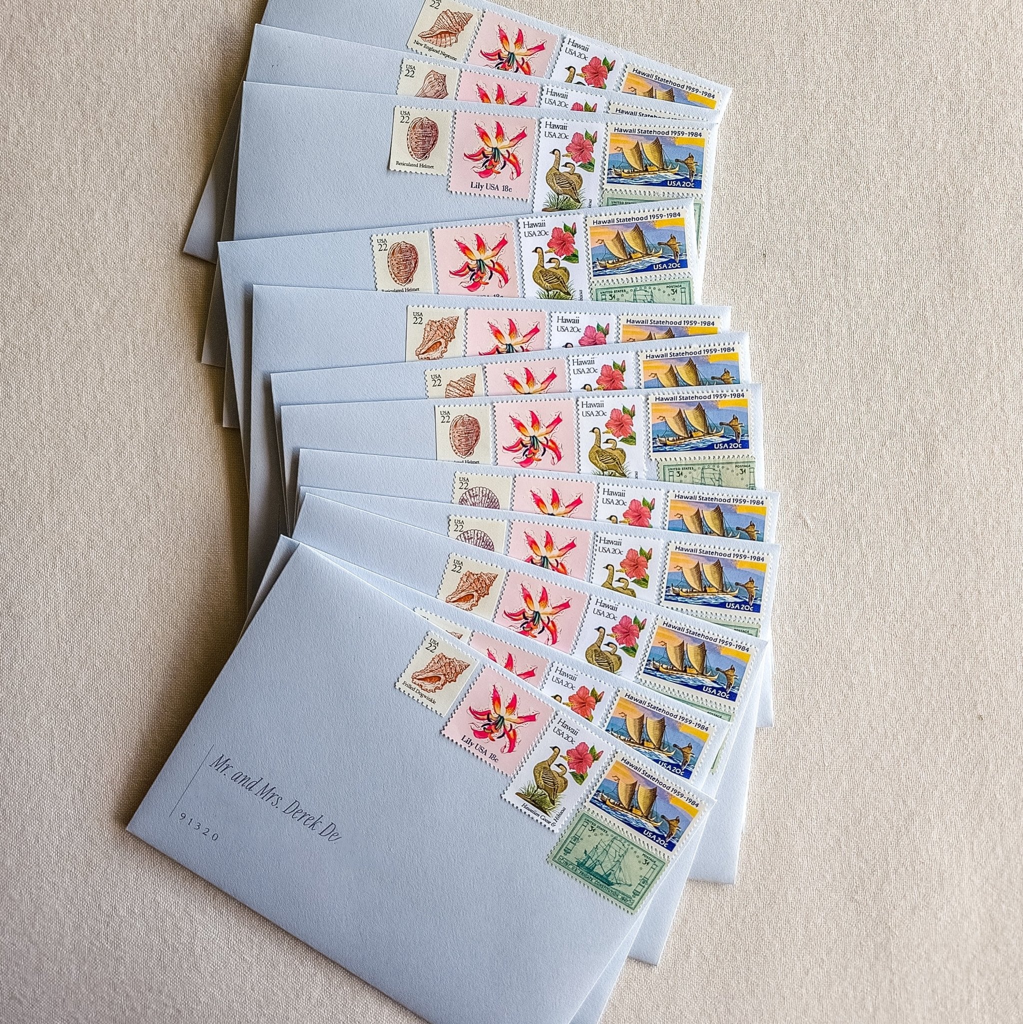 Stack of pale blue wedding envelopes with vintage postage